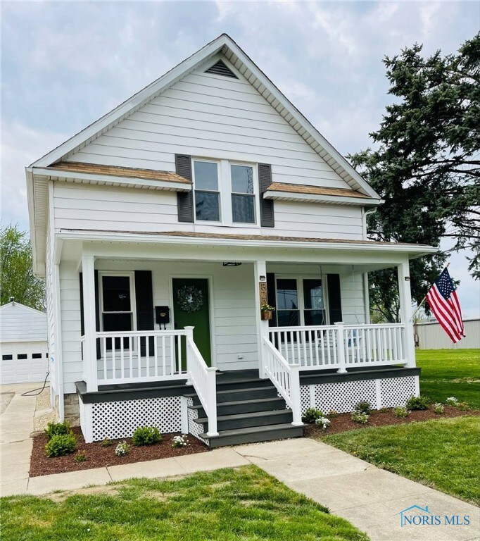 bungalow featuring covered porch, an outbuilding, a front yard, and a garage
