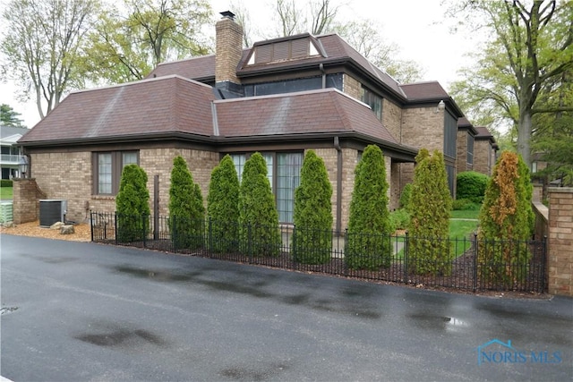 6553 Abbey Run Unit D13, Sylvania, OH 43560 - view of property exterior with brick siding, central AC, fence, and a chimney