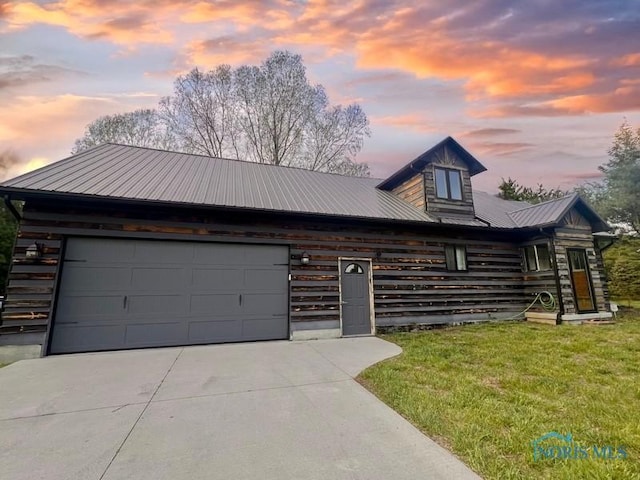 view of front facade featuring an attached garage, concrete driveway, metal roof, and a front yard