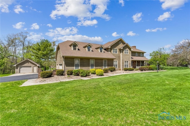 view of front of home with a detached garage, an outbuilding, and a front lawn