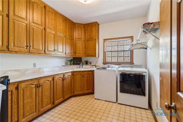 laundry area with light floors, a sink, cabinet space, and washing machine and clothes dryer