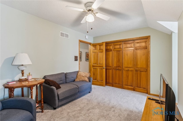 living room featuring carpet floors, ceiling fan, visible vents, and vaulted ceiling