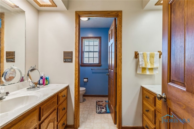 bathroom featuring toilet, baseboards, and vanity