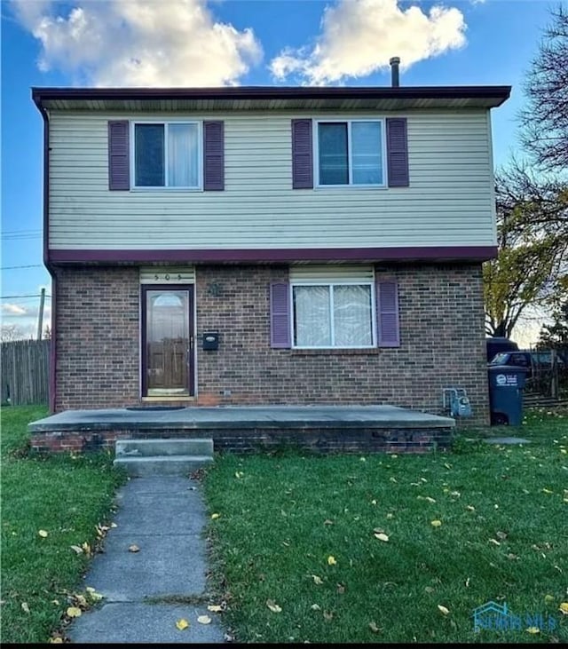 view of front of home featuring fence, a front lawn, and brick siding