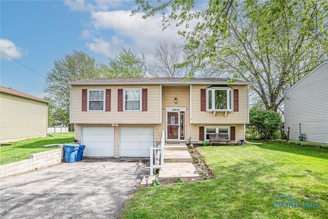 split foyer home with an attached garage, a front lawn, and aphalt driveway