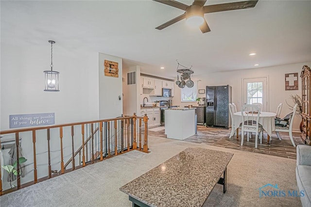 living room with visible vents, ceiling fan with notable chandelier, recessed lighting, and light colored carpet