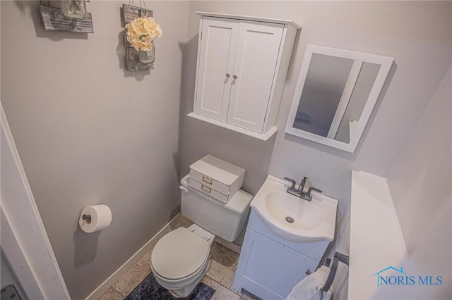 half bath with toilet, baseboards, and vanity