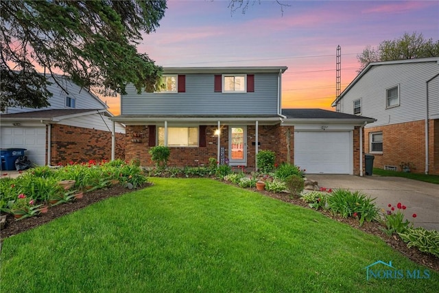 traditional-style house featuring brick siding, a garage, a yard, and driveway