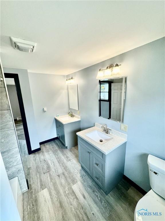 312 Minneapolis St, Defiance, OH 43512 - full bathroom featuring a sink, toilet, wood finished floors, and visible vents