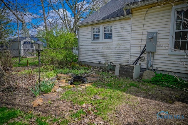 view of home's exterior with fence, a shingled roof, and cooling unit