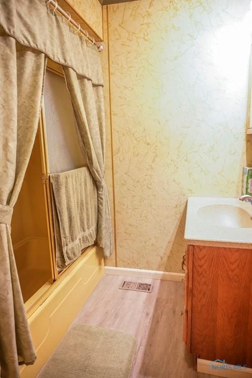 bathroom with shower / bath combination, visible vents, wood finished floors, vanity, and baseboards