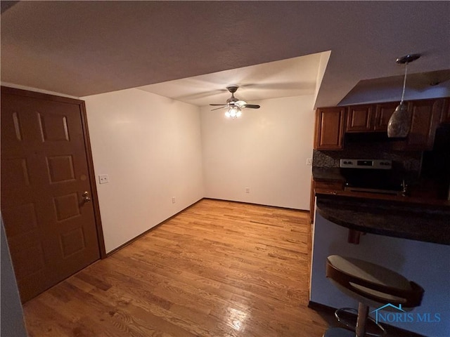 kitchen with ceiling fan, range with electric cooktop, decorative light fixtures, dark countertops, and light wood-style floors