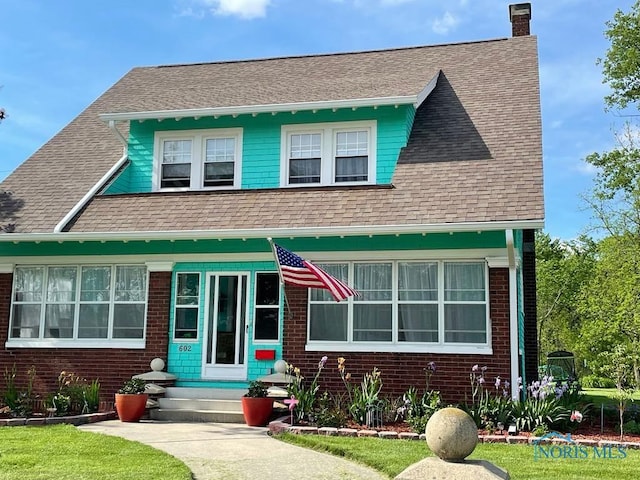 view of front of property featuring brick siding, a shingled roof, and a chimney