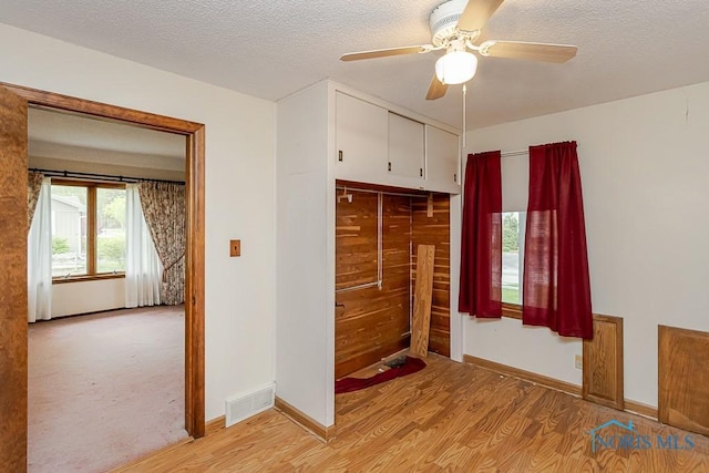unfurnished bedroom featuring a textured ceiling, visible vents, baseboards, a closet, and light wood-style flooring