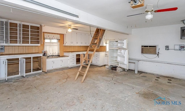 interior space featuring an AC wall unit, concrete flooring, ceiling fan, and white cabinetry