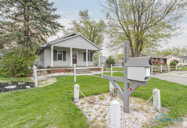 bungalow-style house with covered porch, fence, and a front yard
