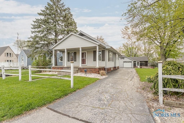 bungalow with a porch, a front yard, an outbuilding, a garage, and fence