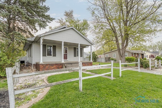 bungalow-style home with fence, covered porch, and a front yard