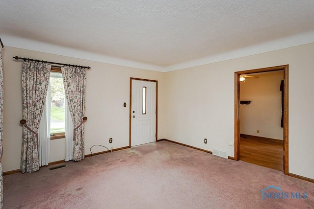 carpeted spare room featuring visible vents and baseboards