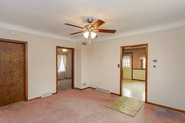 spare room featuring ceiling fan, visible vents, and light carpet