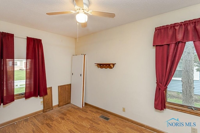 unfurnished room featuring baseboards, ceiling fan, wood finished floors, and visible vents