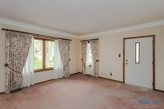 empty room featuring baseboards, a textured ceiling, and carpet floors