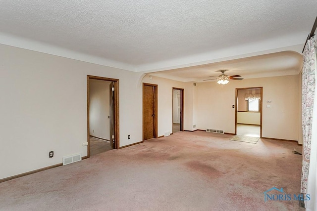 spare room with carpet floors, arched walkways, ceiling fan, and visible vents