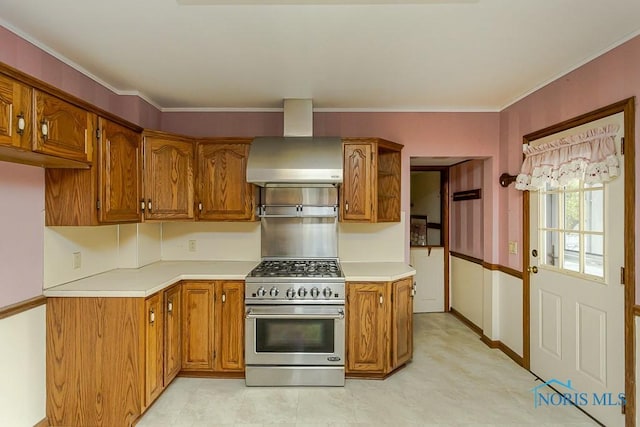 kitchen featuring brown cabinetry, light countertops, stainless steel range, ornamental molding, and wall chimney exhaust hood
