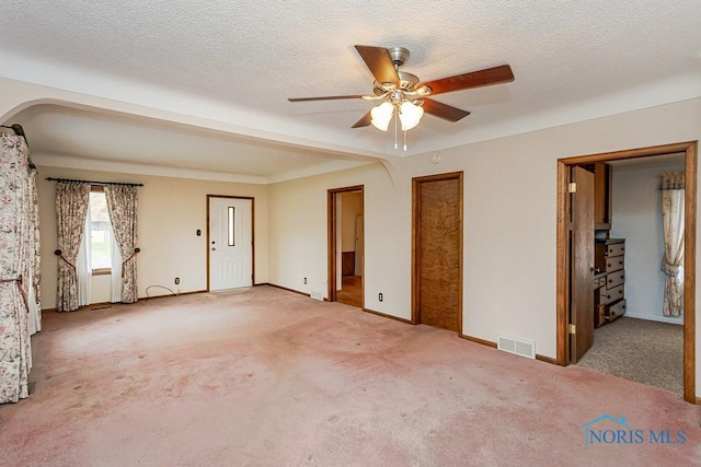 interior space featuring ceiling fan, a textured ceiling, visible vents, carpet floors, and baseboards