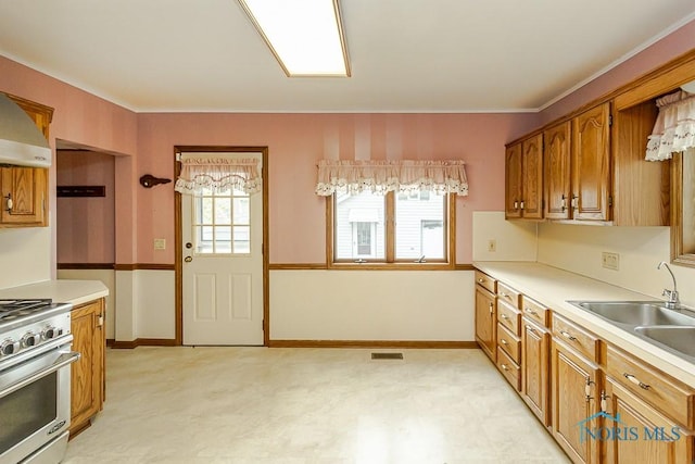kitchen featuring brown cabinets, a sink, stainless steel stove, light countertops, and light floors