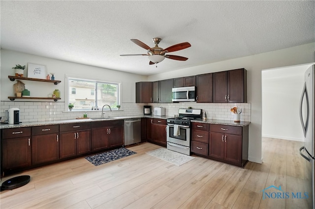 2369 Saint James Woods Blvd, Toledo, OH 43617 - kitchen with stainless steel appliances, a sink, decorative backsplash, ceiling fan, and light wood finished floors
