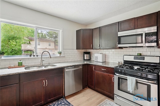 2369 Saint James Woods Blvd, Toledo, OH 43617 - kitchen featuring appliances with stainless steel finishes, a sink, light wood-style flooring, light stone countertops, and a textured ceiling