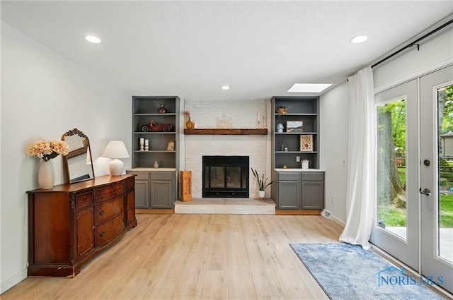 2369 Saint James Woods Blvd, Toledo, OH 43617 - living area featuring light wood-style floors, a brick fireplace, recessed lighting, baseboards, and a textured ceiling