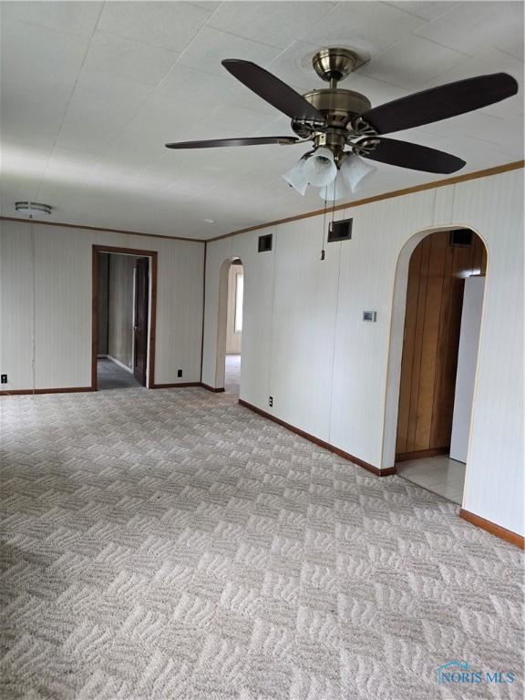 107 Superior St, Oakwood, OH 45873 - carpeted empty room with ceiling fan, visible vents, arched walkways, baseboards, and ornamental molding