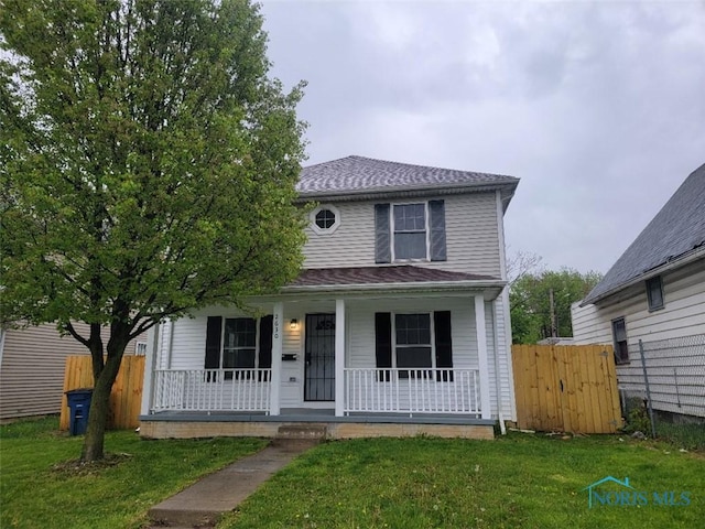 traditional style home featuring a porch, fence, and a front yard