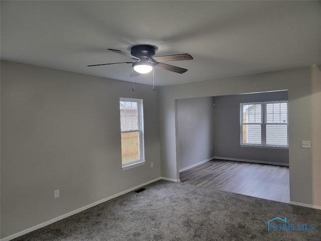 carpeted empty room featuring ceiling fan, visible vents, and baseboards