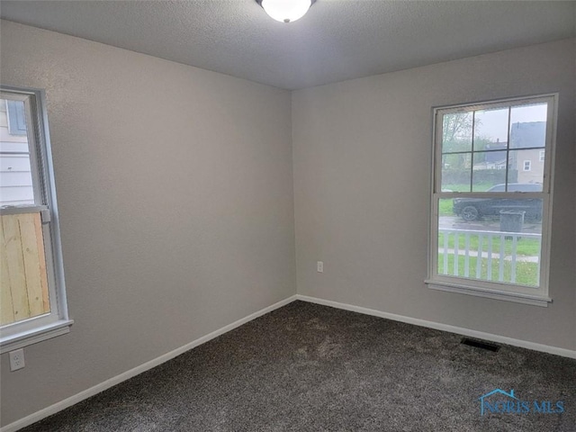 carpeted empty room with visible vents, a textured ceiling, and baseboards