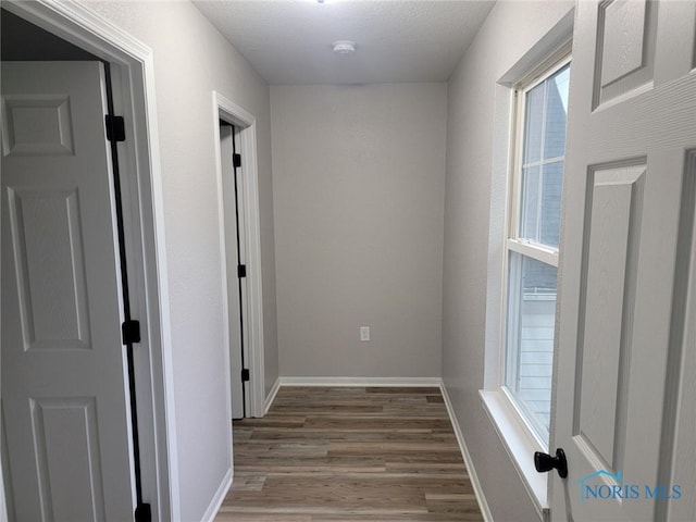 corridor featuring baseboards and wood finished floors
