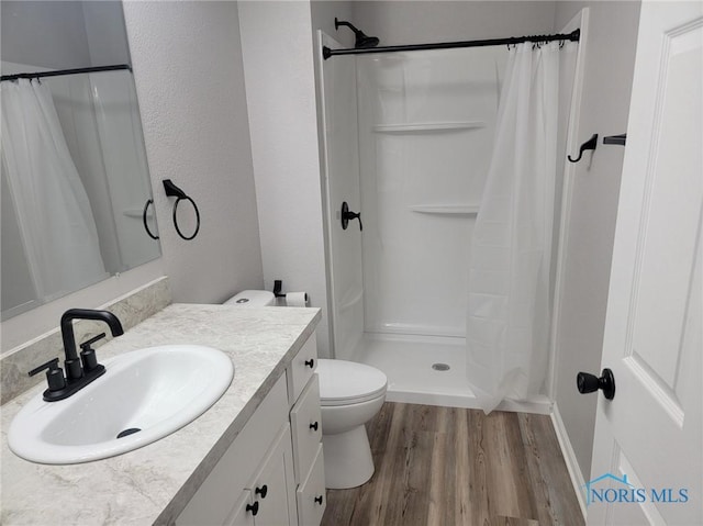 full bathroom with vanity, toilet, baseboards, wood finished floors, and a stall shower