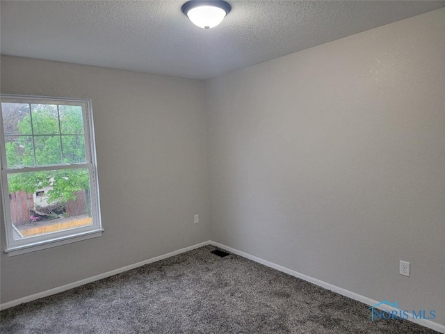 carpeted empty room with visible vents, a textured ceiling, and baseboards