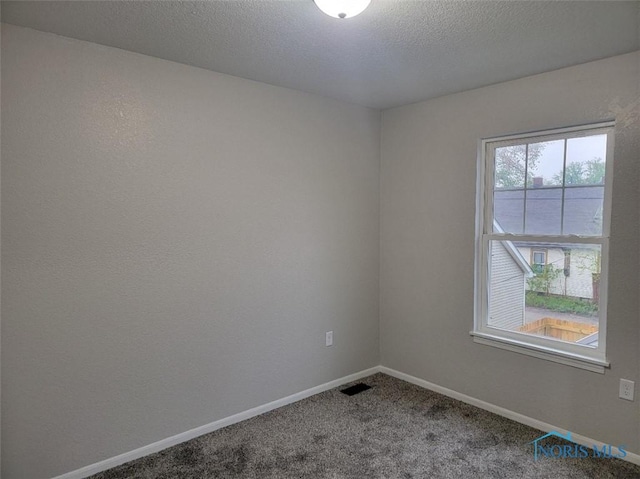 carpeted spare room featuring baseboards, a textured ceiling, and visible vents