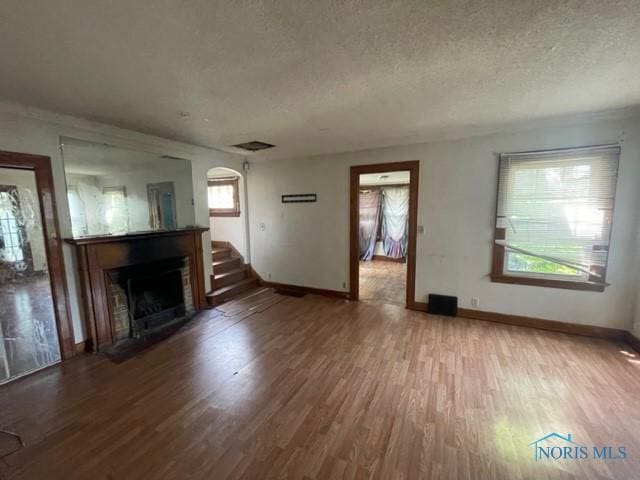 2004 Calumet Ave, Toledo, OH 43607 - unfurnished living room with plenty of natural light, a fireplace with flush hearth, a textured ceiling, and wood finished floors