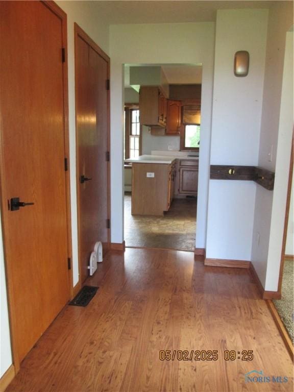 corridor featuring baseboards, light wood finished floors, and visible vents