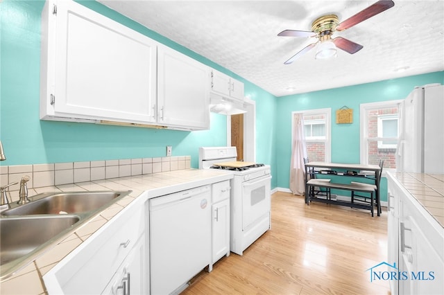 4835 291st St, Toledo, OH 43611 - kitchen featuring white appliances, tile counters, a sink, under cabinet range hood, and white cabinetry