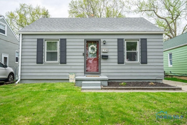view of front of home featuring a front lawn and roof with shingles