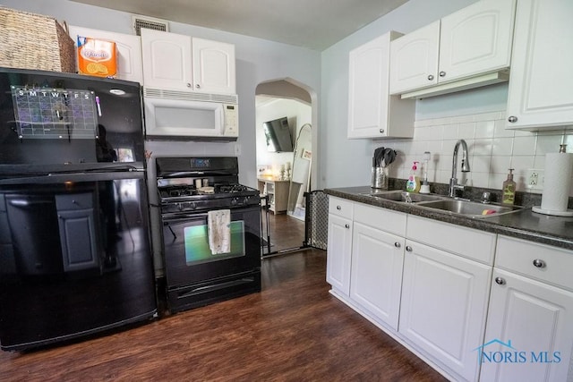 kitchen featuring arched walkways, dark countertops, a sink, and black appliances