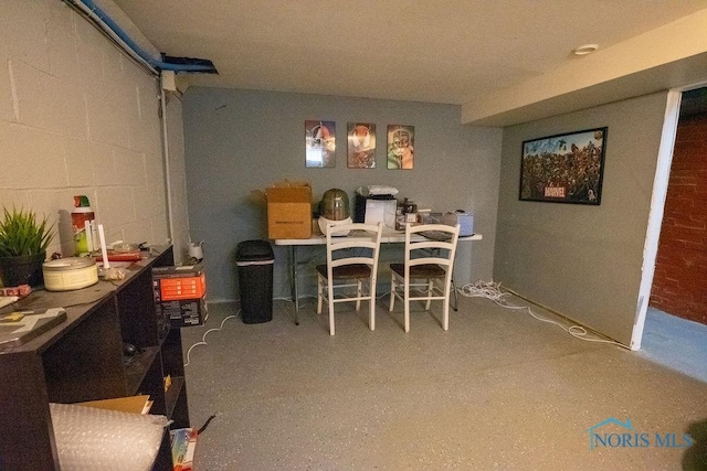 dining area with concrete block wall and speckled floor