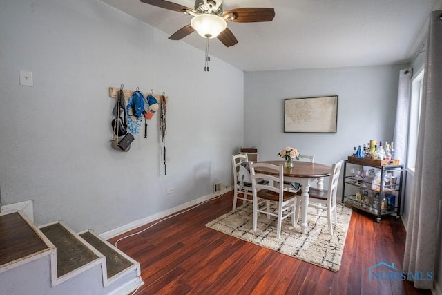 dining space with baseboards, a ceiling fan, and wood finished floors