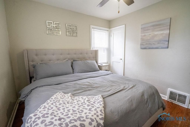 bedroom with visible vents, a ceiling fan, baseboards, and wood finished floors