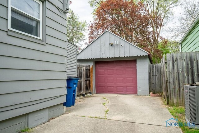 detached garage featuring cooling unit, fence, and concrete driveway